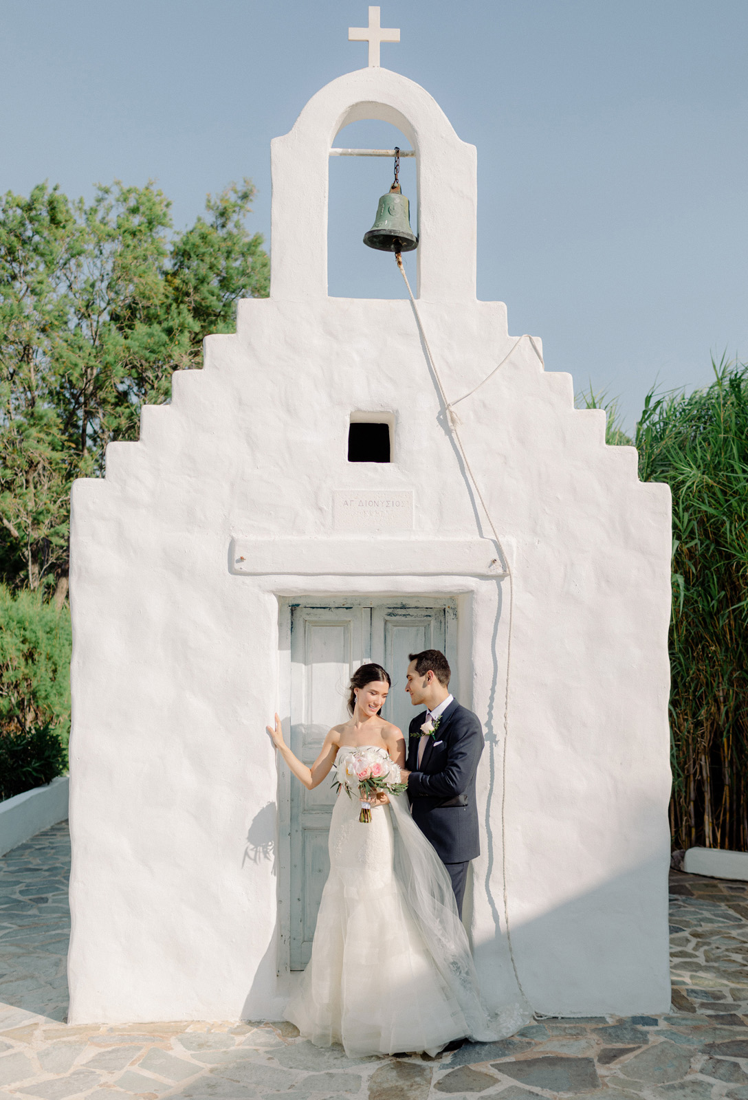 Athens wedding photographer captures couple in front of white washed chapel hugging, wedding in Greece
